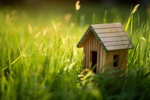 Model of a small wooden house in the grass with copy space. Concept of suburban housing or real estate sale. . photo