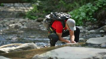 Wanderer Backpacker Trinken Wasser und Waschen seine Hände im ein Fluss. video