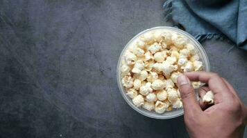 jong Mens aan het eten popcorn van een houder Aan zwart achtergrond video