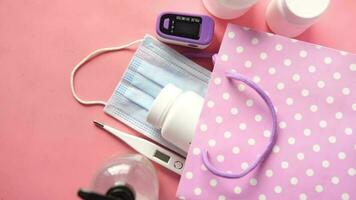 Surgical masks, thermometer and hand sanitizer on pink background video