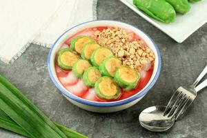 Es Pisang Ijo, Ripe Banana Rolled with Green Thin Crepes. Served with Rice Porridge photo