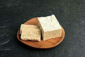 Raw Tempeh or Tempe. Tempeh Slices on Wooden Plate photo