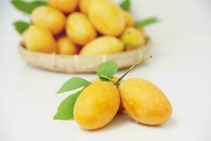 ripe juicy peeled marian plum or plum mango fruit serve in glass bowl and woven bamboo tray over white kitchen background, thailand fresh asian famous tropical fruit photo