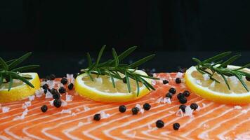 resh raw salmon trout fillet with cooking ingredient herbs rosemary pepper and lemon on dark black stone surface, half body salmon trout top view, healthy rich omega nutrition food appetizer photo