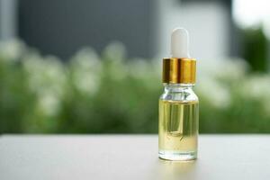 A glass bottle with dropper on the table. Concept of aroma oil, cosmetic, and beauty skin. photo