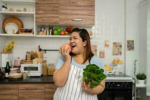 las embarazadas asiáticas aprenden a cocinar comidas saludables de Internet en la cocina, las mujeres gordas preparan una ensalada de verduras para la dieta y pierden peso. concepto de alimentación saludable foto