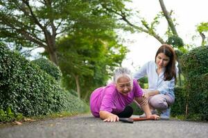 Asian senior woman fell down on lying floor because faint and limb weakness and Crying in pain form accident and her daughter came to help support. Concept of old elderly insurance and health care photo