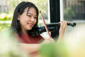 un atractivo mujer aprendizaje músico obras de teatro el violín a hogar. compositor creando canciones con cuerda instrumentos soñador violinista dedos prensado instrumentos de cuerda en violín foto