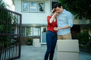 Man comforting his wife and woman hugging her husband and cry in front of the house and full of cardboard boxes during the transport in move out day, moving home concept photo