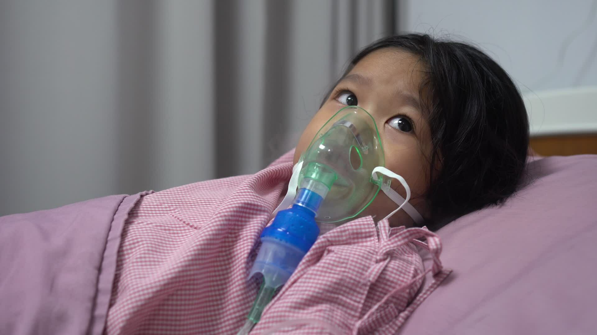 Little Asian girl having an oxygen mask and breathing through a