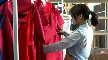 content Jeune asiatique femme couturière mode designer est vérification pour achèvement pour une costume et robe dans une salle d'exposition. concept de Succès Jeune entrepreneur dans le mode entreprise. video