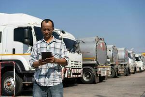 Business owner hold tablet in front of oil truck after performing a pre-trip inspection on a truck. Concept of preventive maintenance. photo