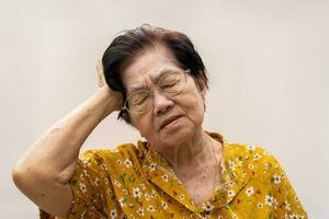 A senior woman who has a severe headache suffers from a stroke ,brain disease,patient holding head with her hand,suffering from senile dementia,memory disorders, confused old elderly with Alzheimer photo