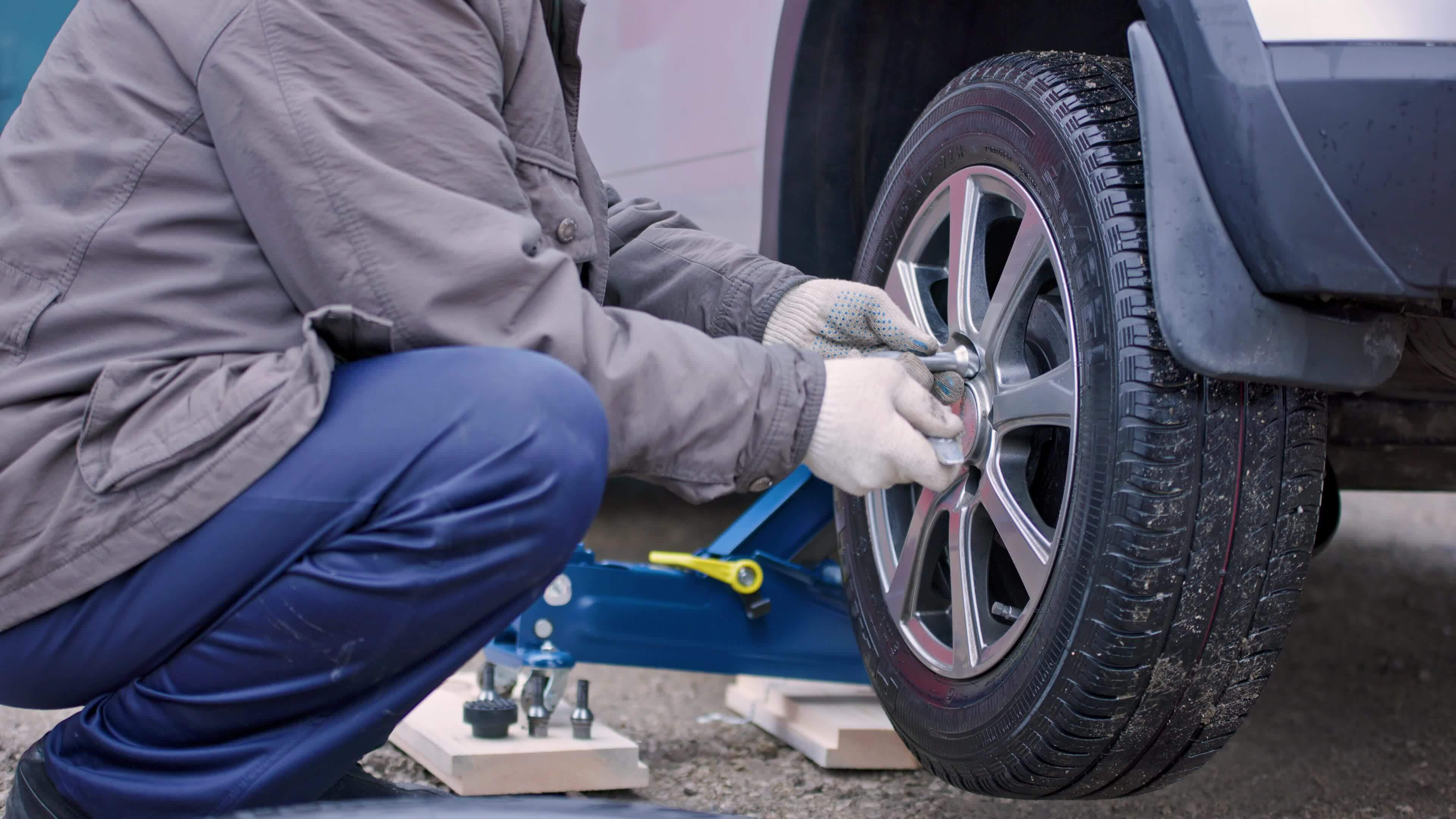 old man in dirty pants removing tire of silver car at cloudy autumn day  24508340 Stock Video at Vecteezy