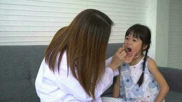 asiatische zahnärztin, die nettes kleines mädchen unterrichtet, das zähne mit zahnbürste und stomatologin putzt, die mädchen über mundhygiene in der zahnklinik, bildung und präventionshöhlenkonzept erzählt. video