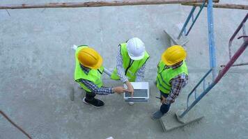 groupe de ingénieur ou architecte mettre sur une casque pour sécurité et Regardez à carnet et parler avec une prestataire pour inspecter bâtiment usine construction sur construction placer. intelligent travail femme concept. video