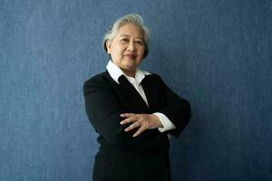 Portrait of middle aged business woman standing isolated on blue background and folded arms looking at the camera with a smile, Successful businesswoman, ceo, director, manager, banker, hr. photo