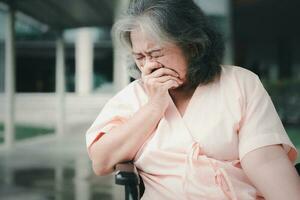 A senior woman in wheelchair who has a severe headache suffers from a stroke, brain disease, patient holding head with hand, suffering from senile dementia, memory, confused old elderly with Alzheimer photo