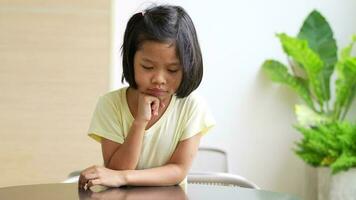 portrait de asiatique enfant 5 année vieux et à collecte cheveux et endroit sa mains sur sa menton et faire en pensant pose, elle est bonheur, éclat dans jeunesse, éducation concept video