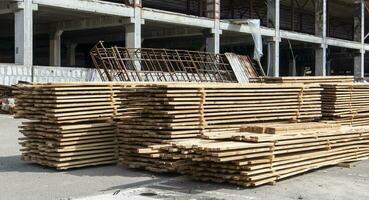 Pile of stacked wooden planks at a construction site. Wooden boards, lumber. Industrial edged timber. Wooden rafters for the repair or construction of a private house. Roofing and joinery lumber. photo