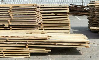 Pile of stacked wooden planks at a construction site. Wooden boards, lumber. Industrial edged timber. Wooden rafters for the repair or construction of a private house. Roofing and joinery lumber. photo