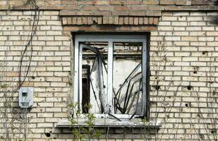 destruido y dañado ventana en el edificio como un resultado de el guerra. el casas fueron destruido y quemado por artillería durante el guerra. roto ventanas un ventana destruido por el lucha. foto