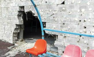 guerra en Ucrania. roto el plastico bancos para aficionados en el podio, en un destruido fútbol americano estadio en un para niños fútbol americano escuela. el Consecuencias de bombardeo desde artillería. foto