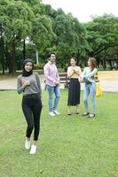 joven asiático malayo chino hombre mujer al aire libre parque libro archivo carpeta ordenador portátil computadora teléfono sentar estar estudiar mezclarse foto