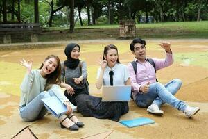 joven asiático malayo chino hombre mujer al aire libre parque libro archivo carpeta ordenador portátil computadora teléfono sentar estar estudiar mezclarse foto