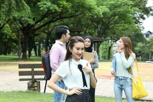 joven asiático malayo chino hombre mujer al aire libre parque libro archivo carpeta ordenador portátil computadora teléfono sentar estar estudiar mezclarse foto