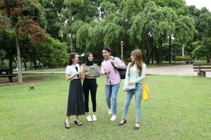 joven asiático malayo chino hombre mujer al aire libre parque libro archivo carpeta ordenador portátil computadora teléfono sentar estar estudiar mezclarse foto