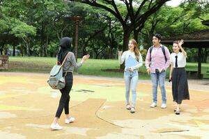 joven asiático malayo chino hombre mujer al aire libre parque libro archivo carpeta ordenador portátil computadora teléfono sentar estar estudiar mezclarse foto