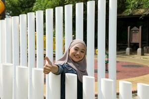 Young Asian Malay man woman outdoor green park walk talk discuss mingle under umbrella photo