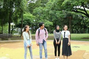 joven asiático malayo chino hombre mujer al aire libre parque caminar estar estudiar hablar discutir punto ordenador portátil archivo libro mochila foto