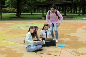 joven asiático malayo chino hombre mujer al aire libre parque libro archivo carpeta ordenador portátil computadora teléfono sentar estar estudiar mezclarse foto