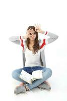 Yong Asian youth girl in casual dress sit on floor book on lap look through hole in hand ok sign expression funny witty on white background photo