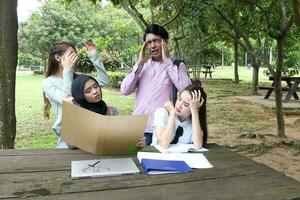 joven asiático malayo chino hombre mujer al aire libre parque libro archivo carpeta ordenador portátil computadora teléfono sentar estar estudiar mezclarse foto