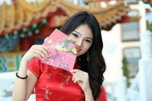 Young south east asian Chinese man woman traditional costume Chinese new year greeting outdoors at temple photo