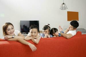 Parent mother father little child boy girl brother sister happy smile looking over the sofa photo