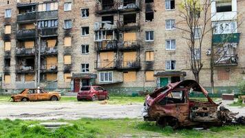 un roto ucranio civil auto, Disparo por artillería, soportes en el patio de un destruido casa. guerra Entre Rusia y Ucrania. el destrucción de un abandonado coche. foto