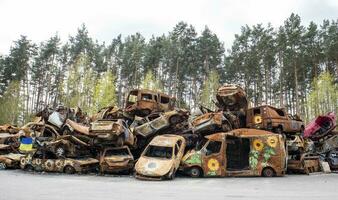 A lot of burnt fired cars in the parking lot, the consequences of the invasion of Ukraine. War in Ukraine. Cemetery of destroyed cars of civilians who tried to evacuate from the war zone. photo