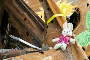 Close-up of a child's toy in ruins after a fire. A soft toy among the cars that burned down as a result of the bombing. A ruined childhood. War concept. Ukraine. Dangerous traffic accident. photo