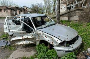 el coche ese quemado abajo después el bombardeo de el ciudad soportes en el patio de un destruido casa. guerra Entre Rusia y Ucrania. fragmentos de un coche después artillería bombardeo. foto