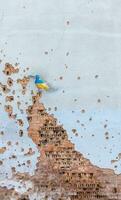 Shelled wall with a drawing of a dove in the colors of the flag of ukraine, blue and yellow. The dove is a symbol of purity, light, peace, love, the human soul. Ukraine, Kyiv - May 06, 2023. photo