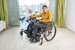 Portrait of young man woman south east Asian malay sitting on wheelchair against window light. Paralyzed waist down. photo