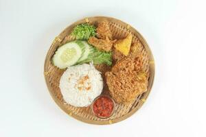Ayam penyet a East Javanese cuisine smashed fried chicken dish with floss sambal slices of cucumbers fried tofu and tempeh photo