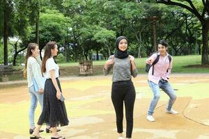 joven asiático malayo chino hombre mujer al aire libre parque caminar estar estudiar hablar discutir punto ordenador portátil archivo libro mochila foto