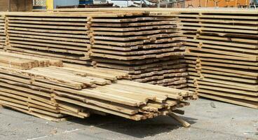 Pile of stacked wooden planks at a construction site. Wooden boards, lumber. Industrial edged timber. Wooden rafters for the repair or construction of a private house. Roofing and joinery lumber. photo