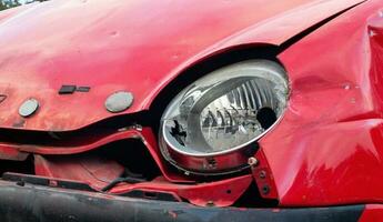 Broken headlight of a red car after a severe accident with a skewed body, after a powerful impact on the side of the road. Traffic accident on the street, damaged car after a collision in the city. photo