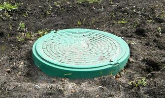 New green metal manhole on the land. Repair work. The closed sunroof does not pose a danger to pedestrians and vehicles. Underground pipeline repair. photo